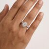 Halo design features an oval shape diamond set in centre with four pear shaped claws surrounded by brilliant cut diamonds